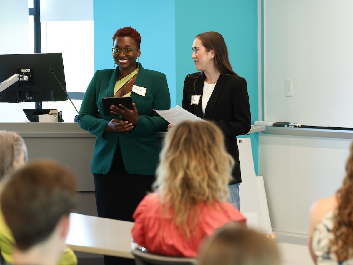 Two female college staff members standing in a classroom giving a lecture