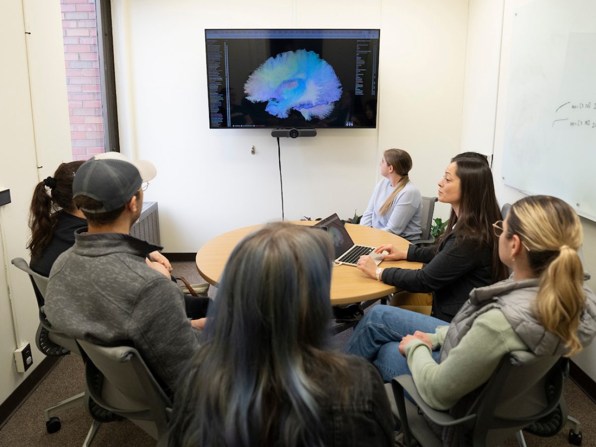 Room full of college students and a teacher looking at a tv screen with a diagram on it
